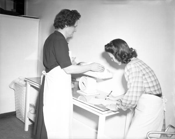 Public health nurse weighing an infant.