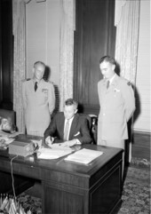 Governor LeRoy Collins signing document for U.S. Navy Captain Winslow and unidentified man.