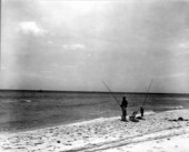 Man and boy on the beach fishing.