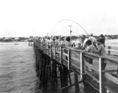 Two boys and many adults fishing on the pier - Jacksonville Beach, Florida.