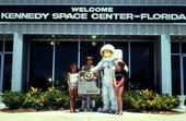 Person wearing space suit standing with visitors in front of the Kennedy Space Center on Merritt Island near Titusville, Florida.