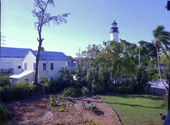 View of the grounds on the south side of the Hemingway museum with the Key West Lighthouse in the background - Key West, Florida.