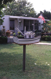 Miniature boat sculpture on display in a yard