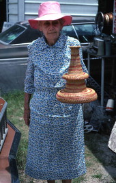 Myrtle McCoey holding a pine needle craft she made