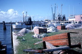 Nets piled by the docks with docked fishing boats in the background- Jacksonville, Florida.