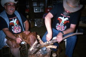 Apprentice Randy Stewart stripping bark off a white oak tree as his teacher Bobby Johns looks on