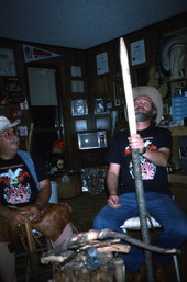 Apprentice Randy Stewart looking over a white oak tree that he has stripped of bark as his teacher Bobby Johns looks on