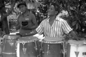 Florencio Baro playing conga drums while his apprentice Marcial Hernandez accompanies him on a cow bell - Miami, Florida