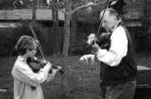 Apprentice Andrew Cook learning the art of twin fiddling from his mentor George Custer.