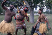 Nigerian acrobatic dancers Augustine and Felix Omeben preparing to eat fire while apprentice Akila Baki observes - North Miami, Florida.