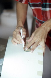 Hands of Sylvia Garcia marking place to put ears on Mickey Mouse head pinata she is making - West Palm Beach, Florida.
