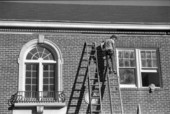 Worker on a ladder works on a building - Tallahassee, Florida.