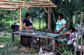 Mary B. Billie and daughter Claudia C. John by a table under a partially built chickee - Big Cypress Reservation, Florida
