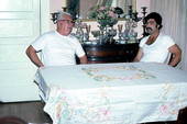 Greek American men sitting with a tablecloth which is an example of Greek needlework