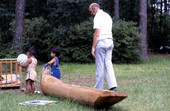 Man standing in a canoe while children play around it - White Springs, Florida
