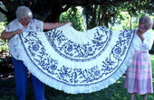 Two women holding up an example of reverse applique needlework done by Fula Peleti