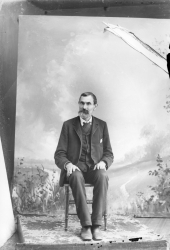 Seated man with full goatee.