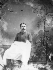Seated man with a cloth covering his lap.