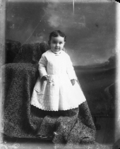 Standing child, holding a rattle.