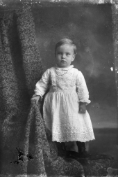 Child standing in white dress.