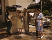 People receiving free copies of the Evening Independent from a paper carrier on a rainy day in St. Petersburg, Florida.