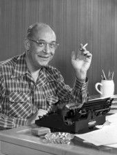 Portrait of author Eric Hodgins sitting at his typewriter.