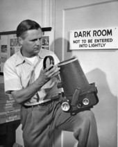 Joe Steinmetz with an F-8 Fairchild aerial camera at the entrance to the darkroom at his studio in Sarasota, Florida.