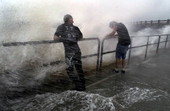 Unidentified men standing in surging waves caused by Hurricane Georges