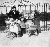 Nursemaid with baby in carriage, boy and girl with doll carriage