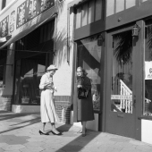 Two women standing on sidewalk in front of store