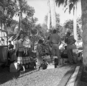 Group of people standing outside near a Christmas tree and opened packages