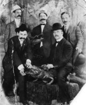 Five men posing with two stuffed alligators
