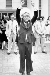 Bob Graham points to the sky wearing a Native American headress