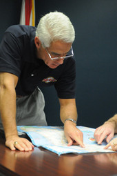 View of Governor Charlie Crist looking at map during a Division of Emergency Management meeting for Tropical Storm Fay.