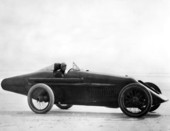 Tommy Milton in his race car at the beach.