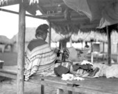 Seminole woman sewing and tending baby in hammock