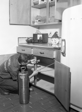 Capital Pest Control employee using a spray on cabinets.