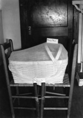 View showing a baby's bed with mosquito net sitting atop two chairs tied for safety.