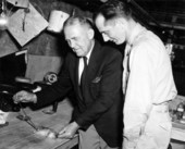 Unidentified men viewing a dead rat.