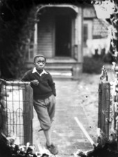 African American boy leaning on a fence.