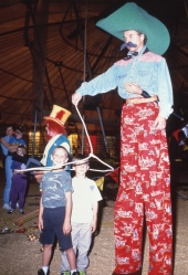 Cowboy on stilts with children at the FSU Flying High Circus in Tallahassee, Florida.