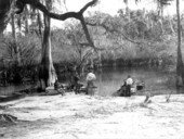 Men with boats on the shore at the Suwannee River .