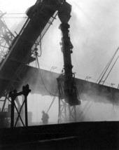 Telescopic chute is lowered into cargo hold to load ship..