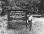 Game and fish officer Buster Hudson standing next to sign at the Gulf Hammock Wildlife Management Area