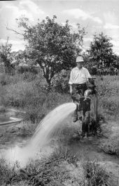 A man stands behind a flowing artesian well - Tampa, Florida.